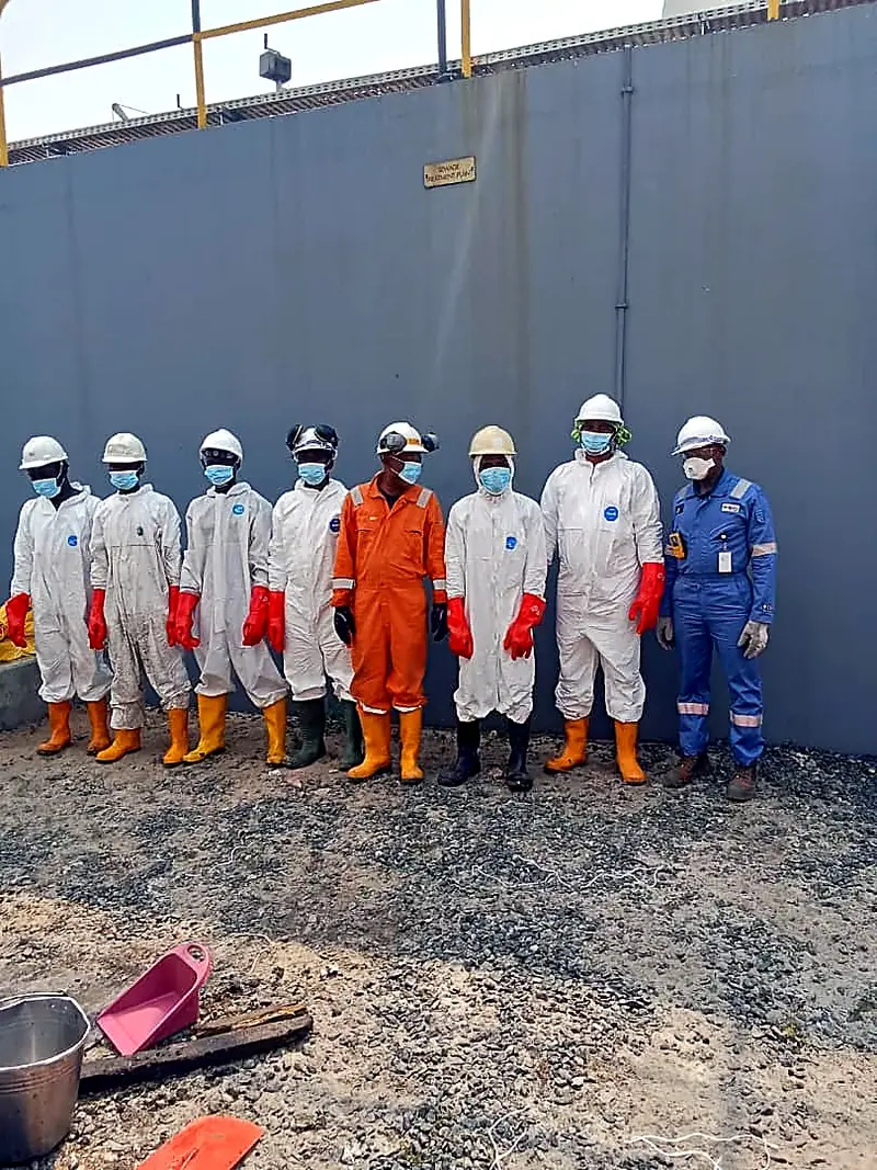 Personnel in protective coveralls lined up on site