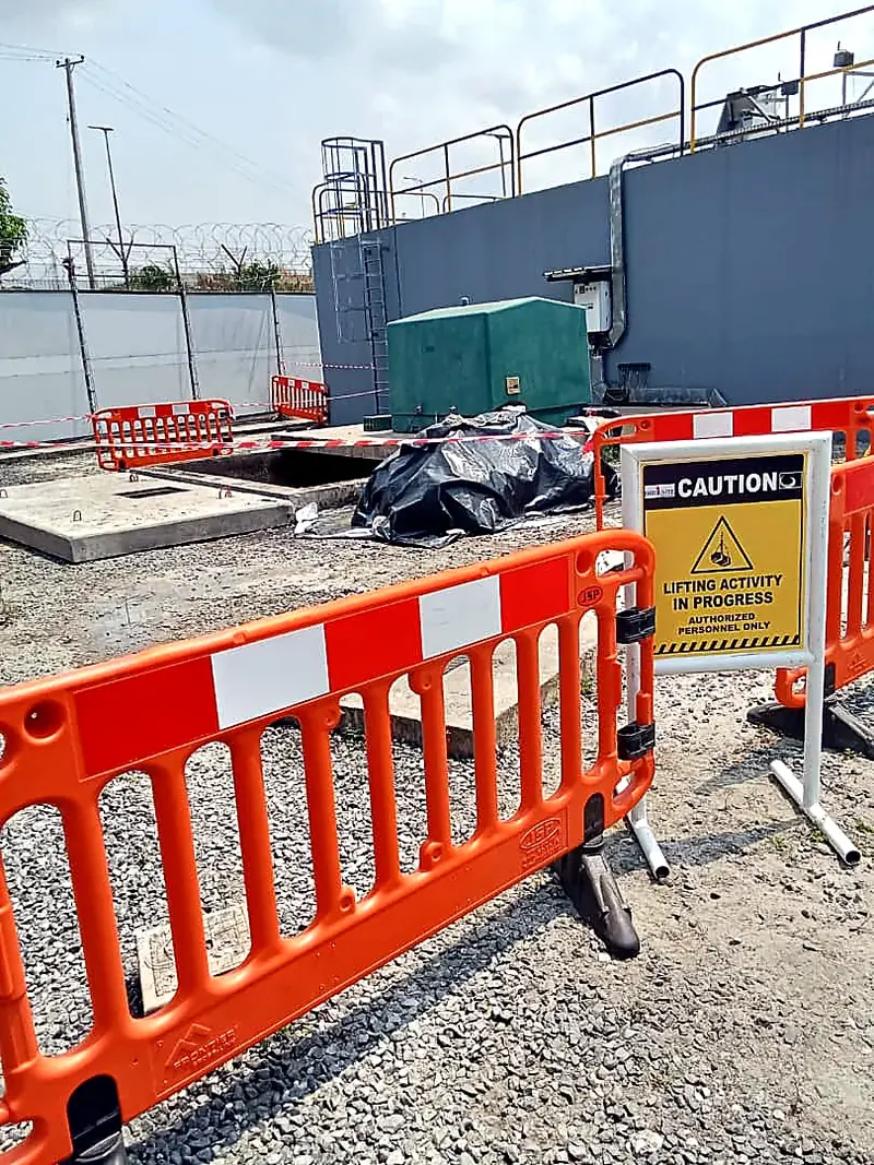 Orange safety barriers and a caution sign at a site work area