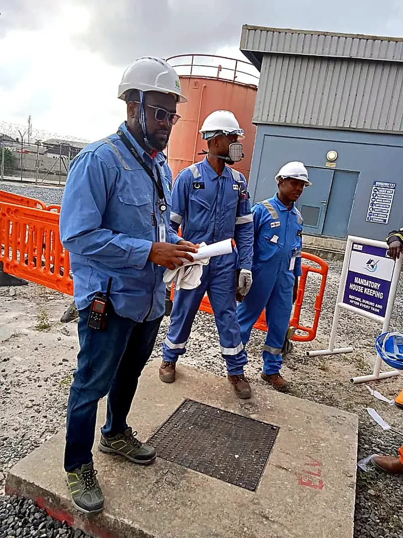 Three team members in blue coveralls reviewing documents on site