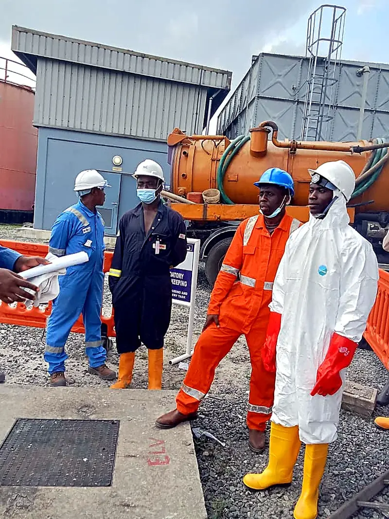 Team in coveralls and hard hats beside a tanker vehicle