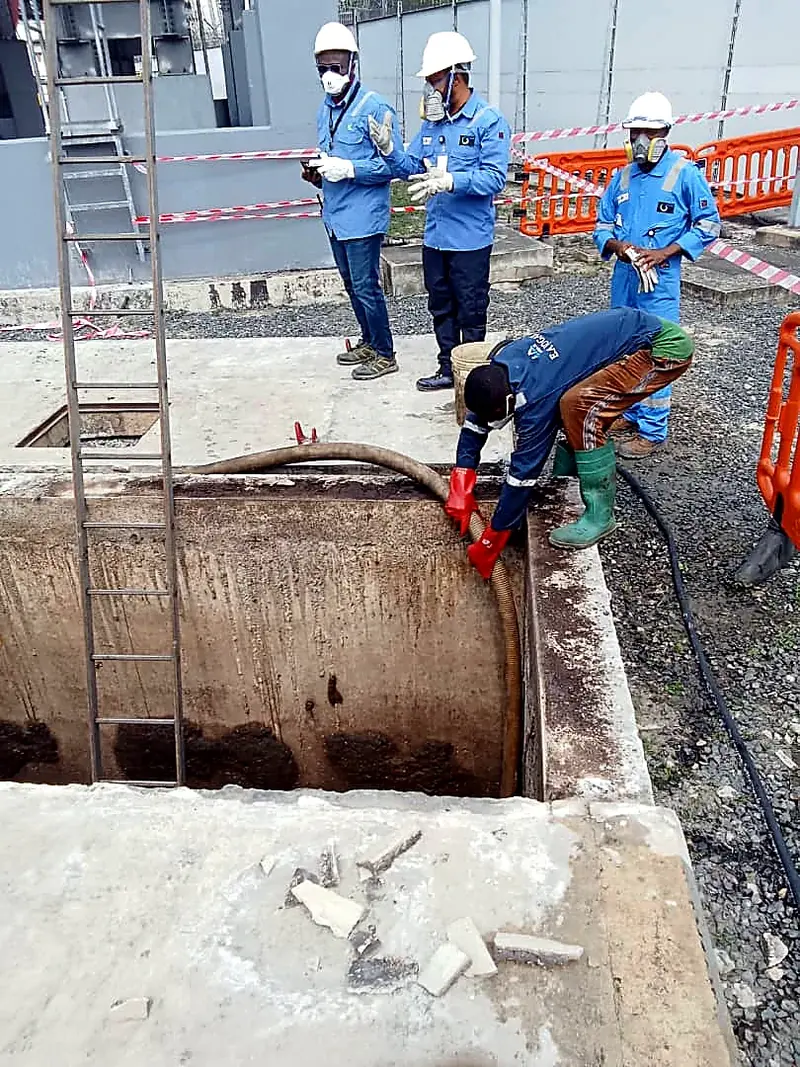 Technicians working at the edge of an open concrete chamber